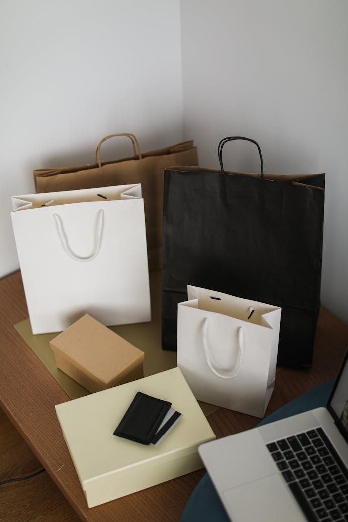 Arranged shopping bags and laptop on a wooden table, representing online shopping.